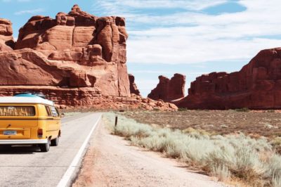 A yellow van travels along a road into the entrance of Arches National Park