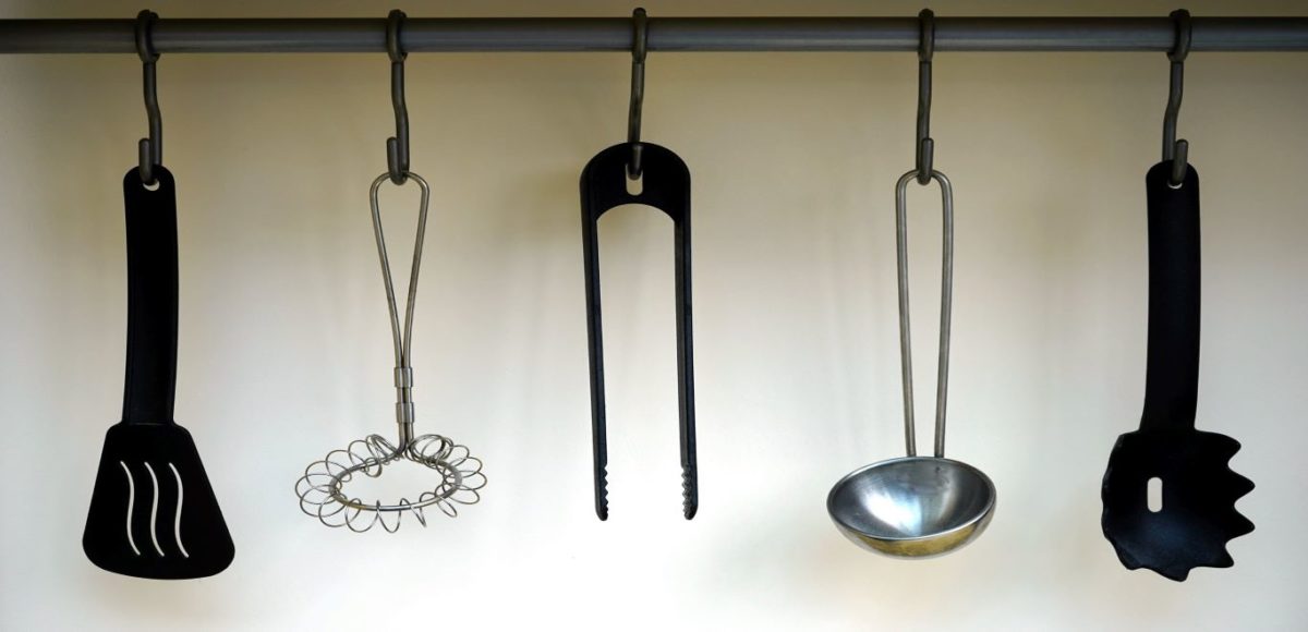 Kitchen utensils hanging under a shelf