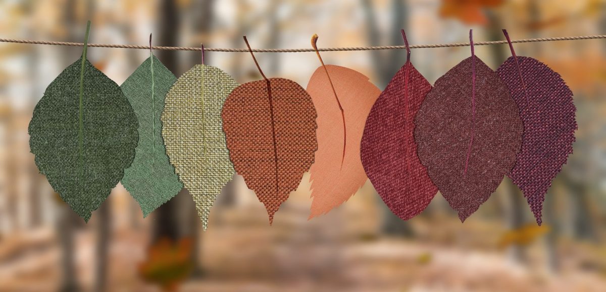 Fabric leaves in green, red, orange, and purple colors hanging from twine outdoors