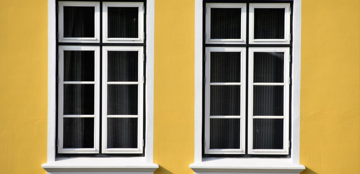 White frame windows on a yellow wall
