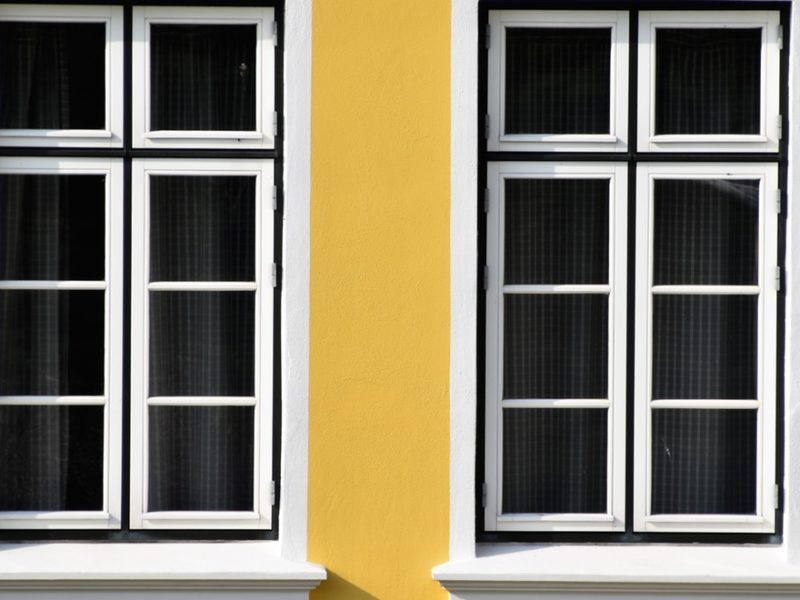 White frame windows on a yellow wall