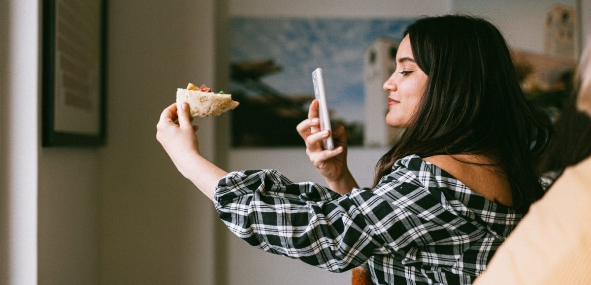 Girl taking a picture of a slice of pizza