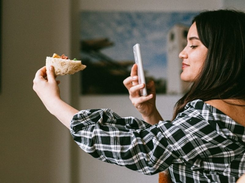 Girl taking a picture of a slice of pizza