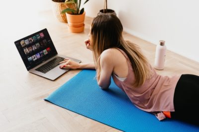 Woman on her computer lying on a yoga mat