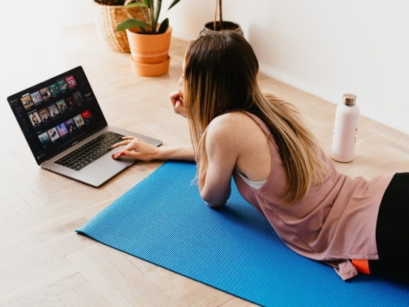 Woman on her computer lying on a yoga mat