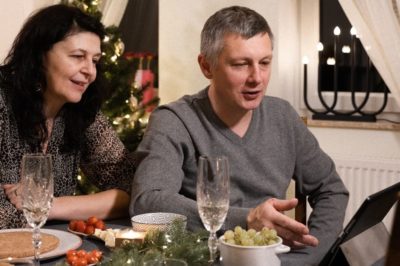 Couple at dinner table talking to someone on a device