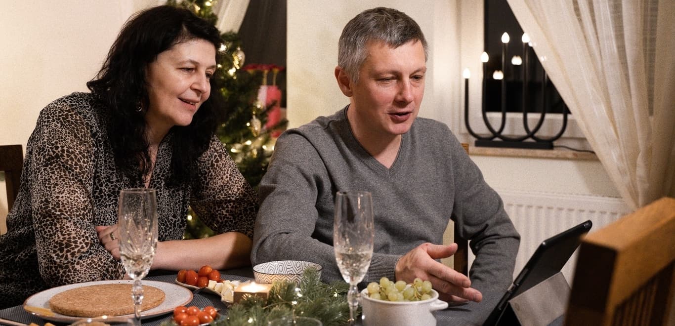 Couple at dinner table talking to someone on a device