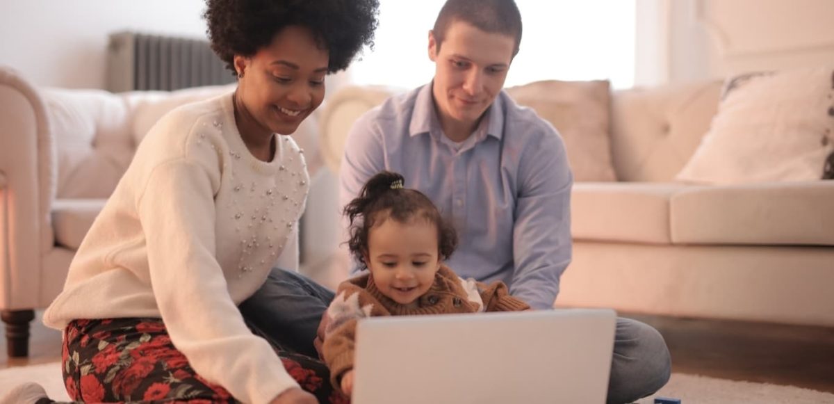 Two parents sitting in front of computer with infant child