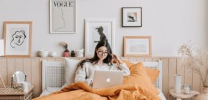Woman doing work in bed in a bohemian styled bedroom