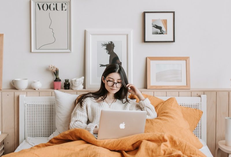 Woman doing work in bed in a bohemian styled bedroom