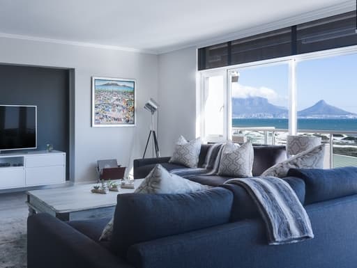Blue-themed living room with view of an ocean mountains outside of large windows.