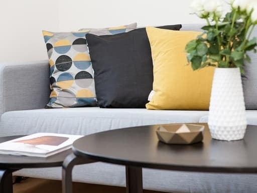 Gray sofa with yellow, black, and blue accent pillows.