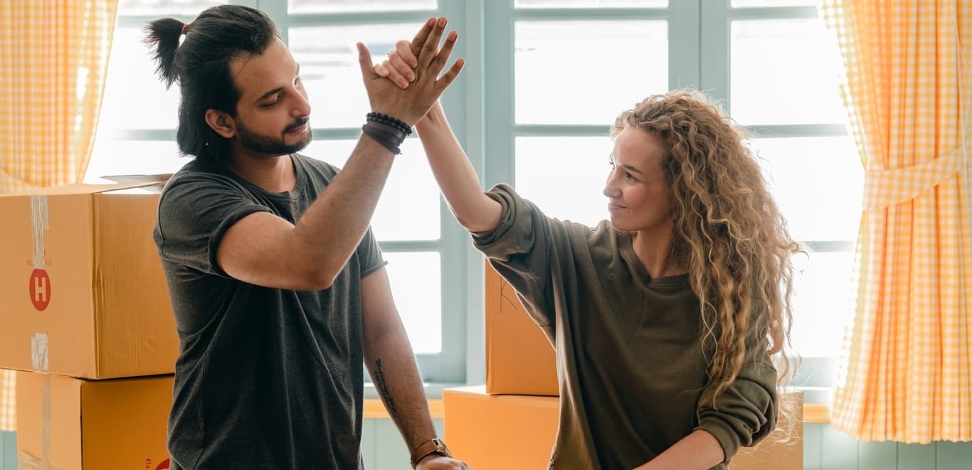 Couple high-fiving in room with boxes