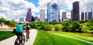 Man and woman riding bikes on a trail with Downtown Houston in the backdrop.