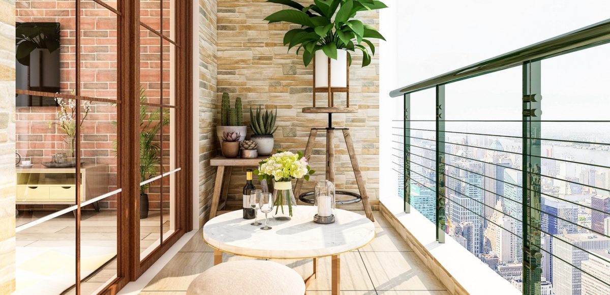 Apartment balcony with a small table and stool, with plants in the background