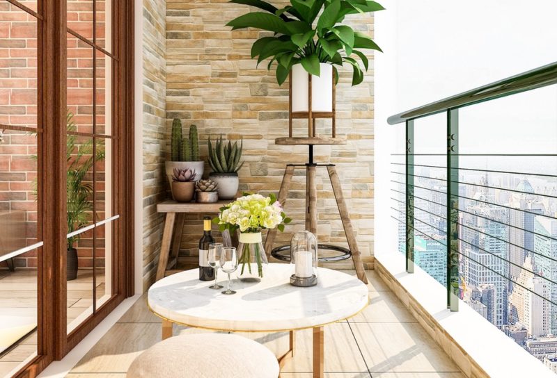 Apartment balcony with a small table and stool, with plants in the background