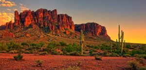 Arizona desert setting with canyons and cacti at sunset.