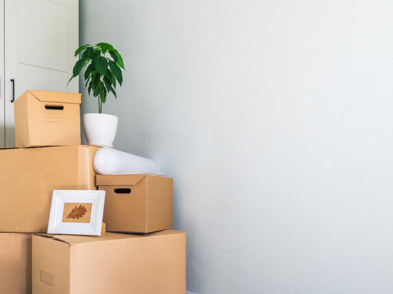Brown moving boxes and personal items are stacked up as someone is preparing to relocate to another state.