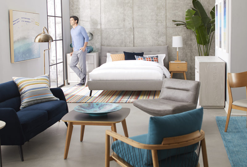 A man stands in a well decorated studio apartment looking out the window