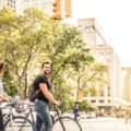 Young couple walking in big city street with bicycles enjoying city vs suburbs