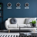 Dark blue moody interior design example with white couch, black furniture, black and white rug, and dark blue walls