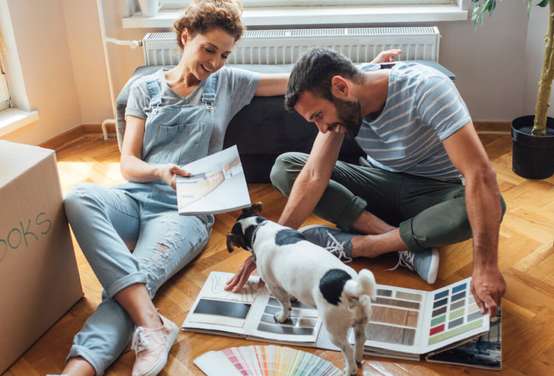 Couple sitting in new home after moving in waiting for furniture to arrive working on selecting paint colors.