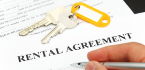 rental agreement form with signing hand and keys and pen