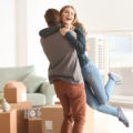Young happy couple in room with moving boxes at new home