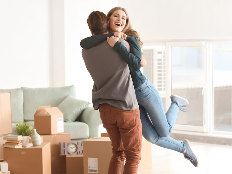 Young happy couple in room with moving boxes at new home