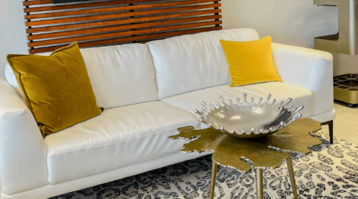 A neutral white sofa with gold and yellow throw pillows