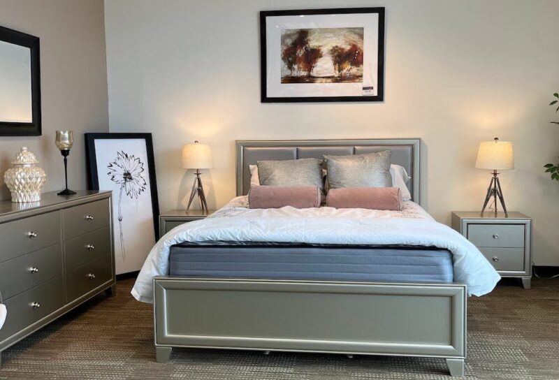 A soft-lit bedroom with romantic, mauve pillows on a light-colored bed.