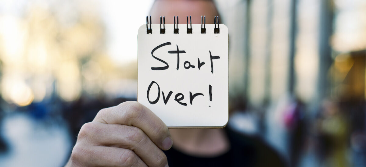 Man holding up a sign that says "start over!"