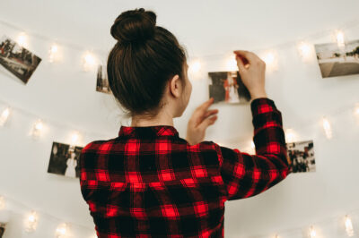 A woman hanging photos on twinkling lights.