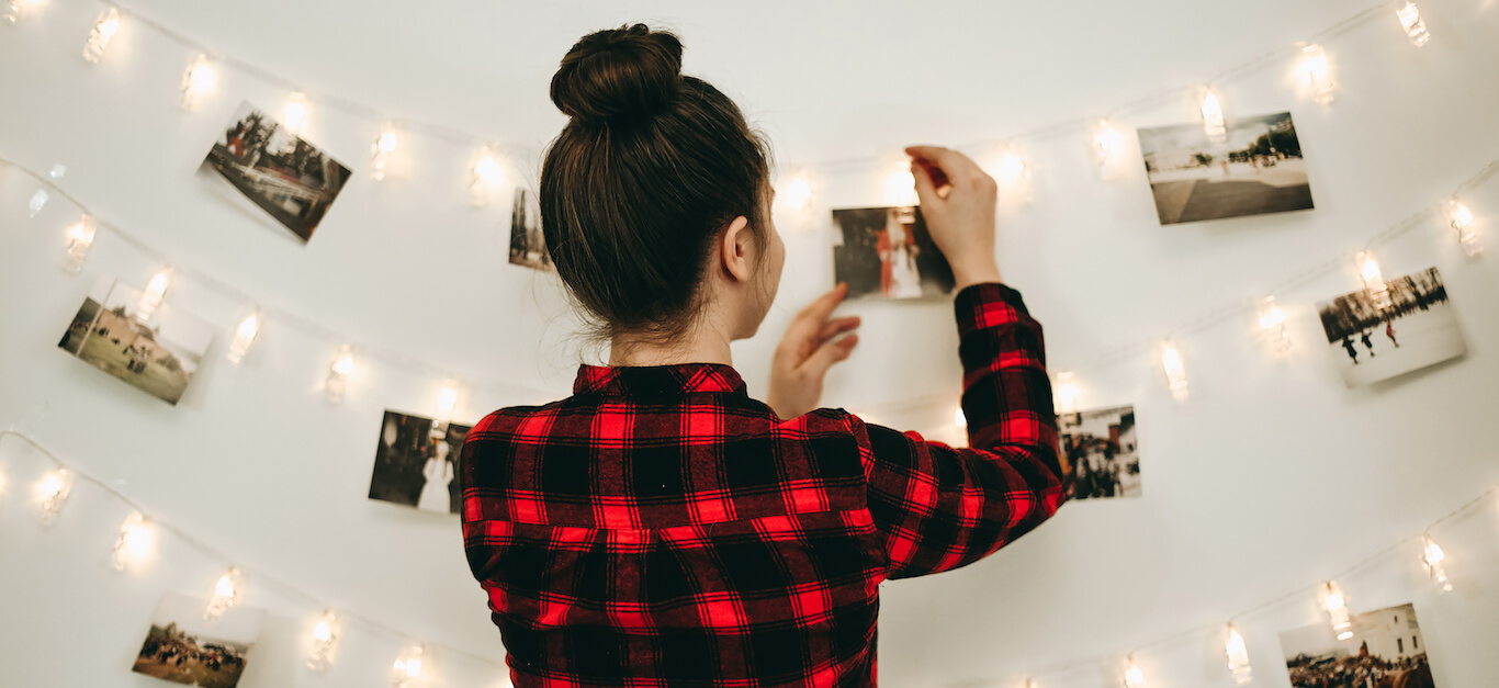 A woman hanging photos on twinkling lights.
