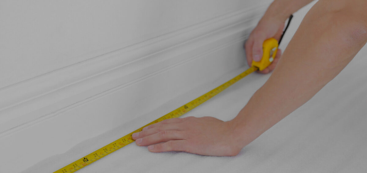A person using a tape measure to measure the size of a room.