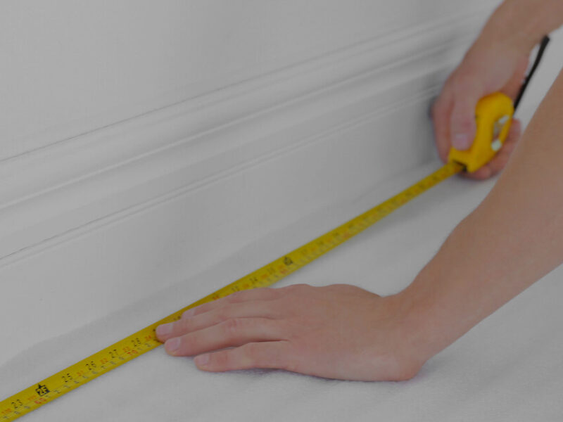 A person using a tape measure to measure the size of a room.