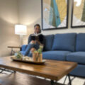 A person reading on a stylish blue couch.