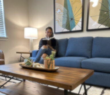 A person reading on a stylish blue couch.