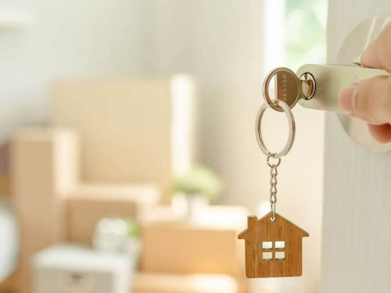 A person opening the door to a new apartment, with boxes in the background.