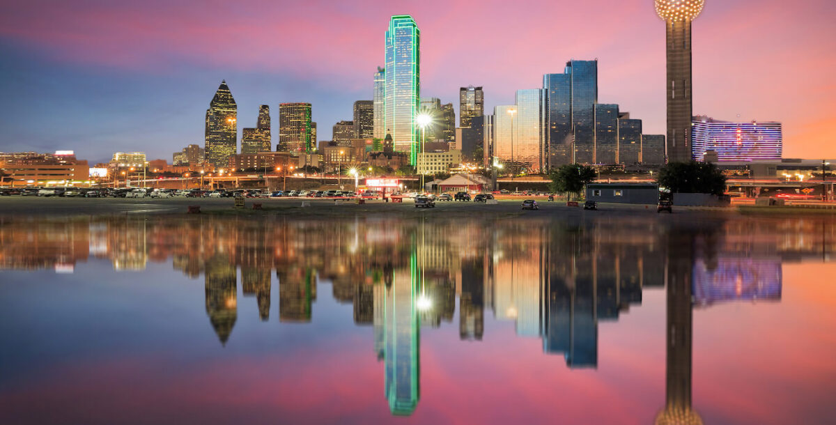 The Dallas skyline with a pink and blue sunset behind it.
