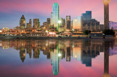 The Dallas skyline with a pink and blue sunset behind it.