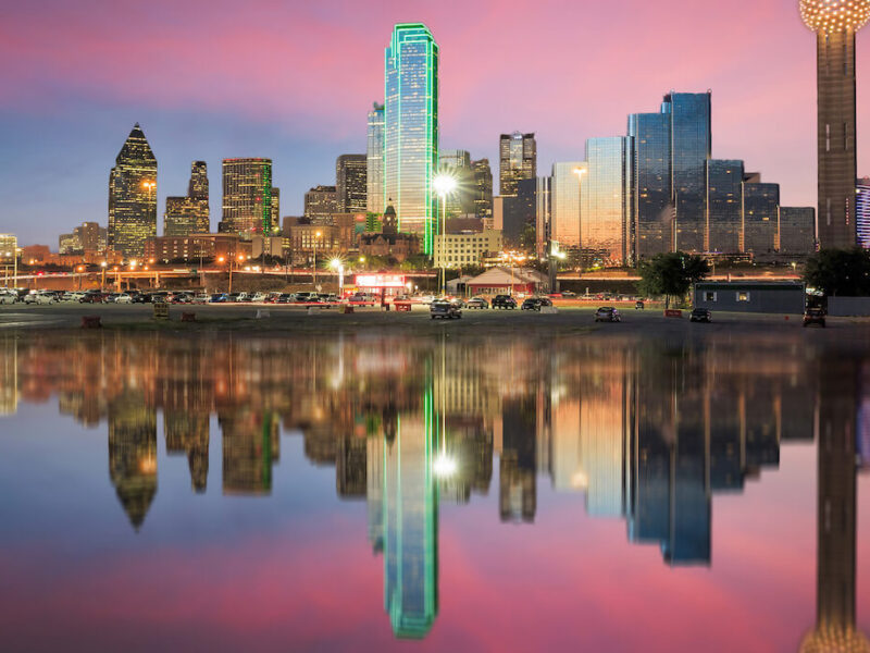 The Dallas skyline with a pink and blue sunset behind it.