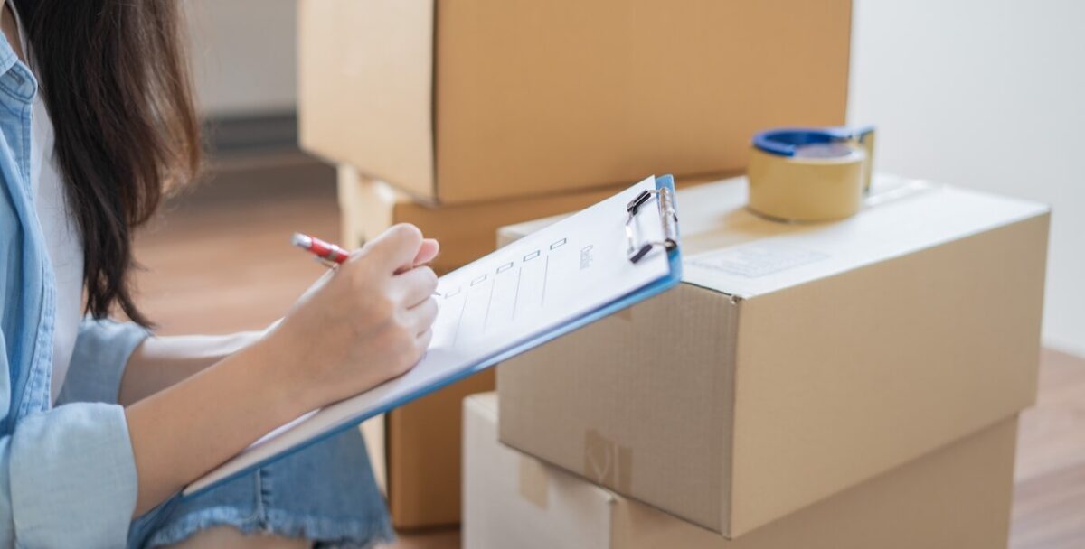 A woman checking items off her relocation checklist in front of a pile of boxes.