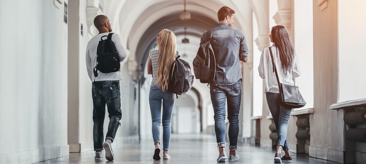 A group of young students walking through the hallways of their college.