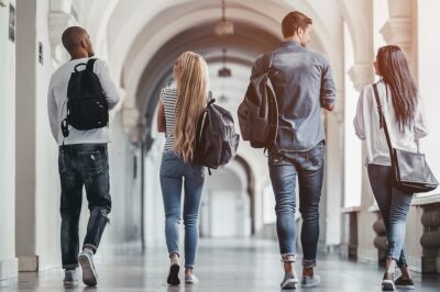 A group of young students walking through the hallways of their college.