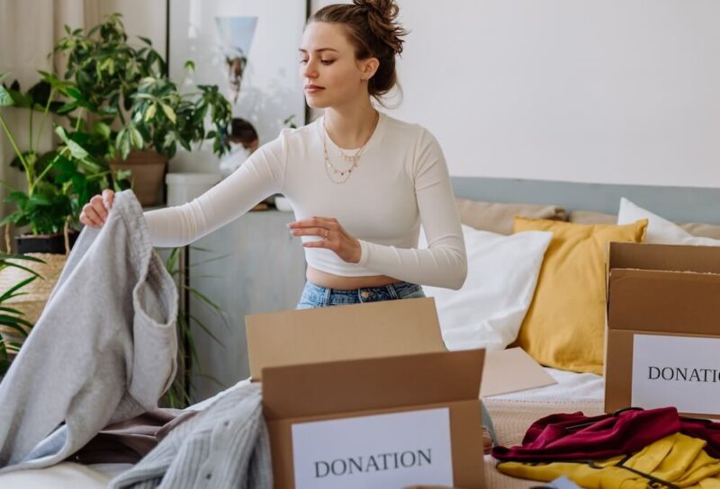 A woman sorting clothes into boxes labeled 