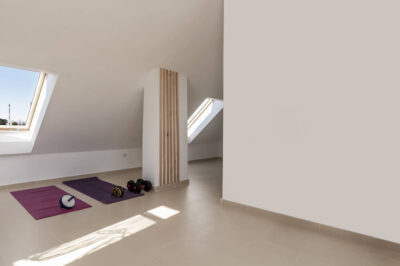 A bright white room with slanted ceilings and exercise equipment on the ground.