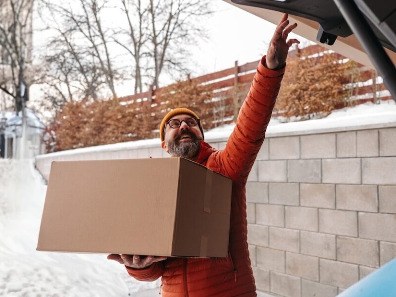 A man loading boxes into a car in the snow.