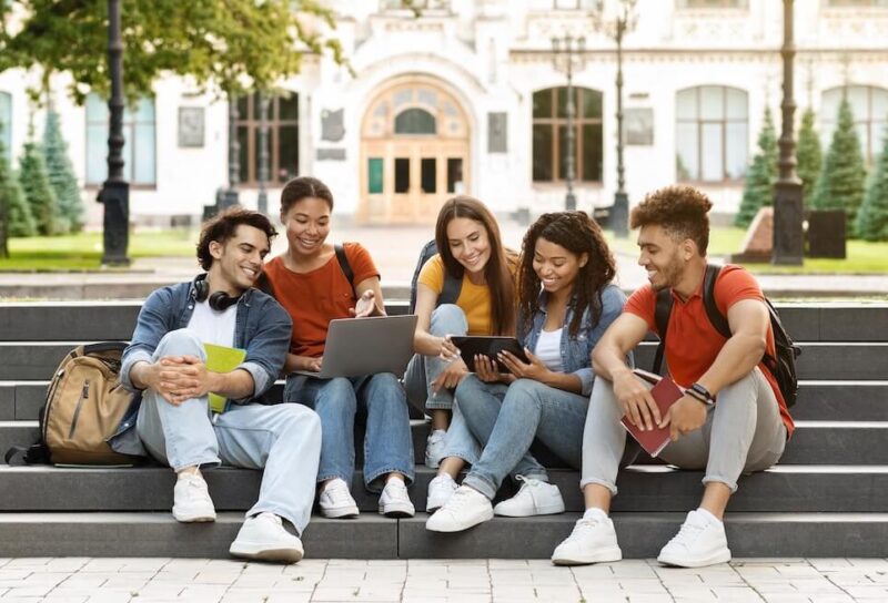 A group of college students sitting in a grassy courtyard.