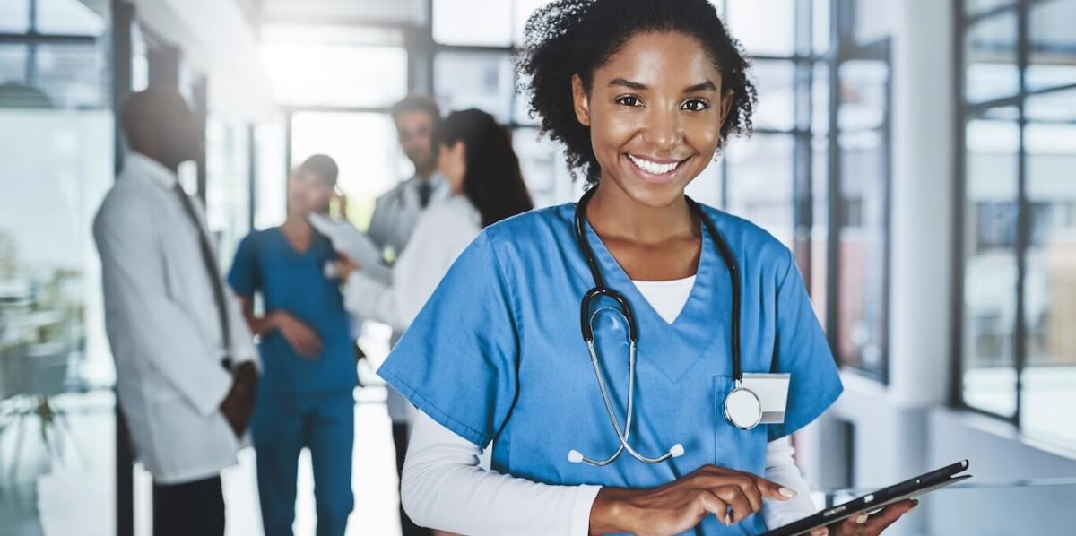 A young doctor in scrubs using a tablet.